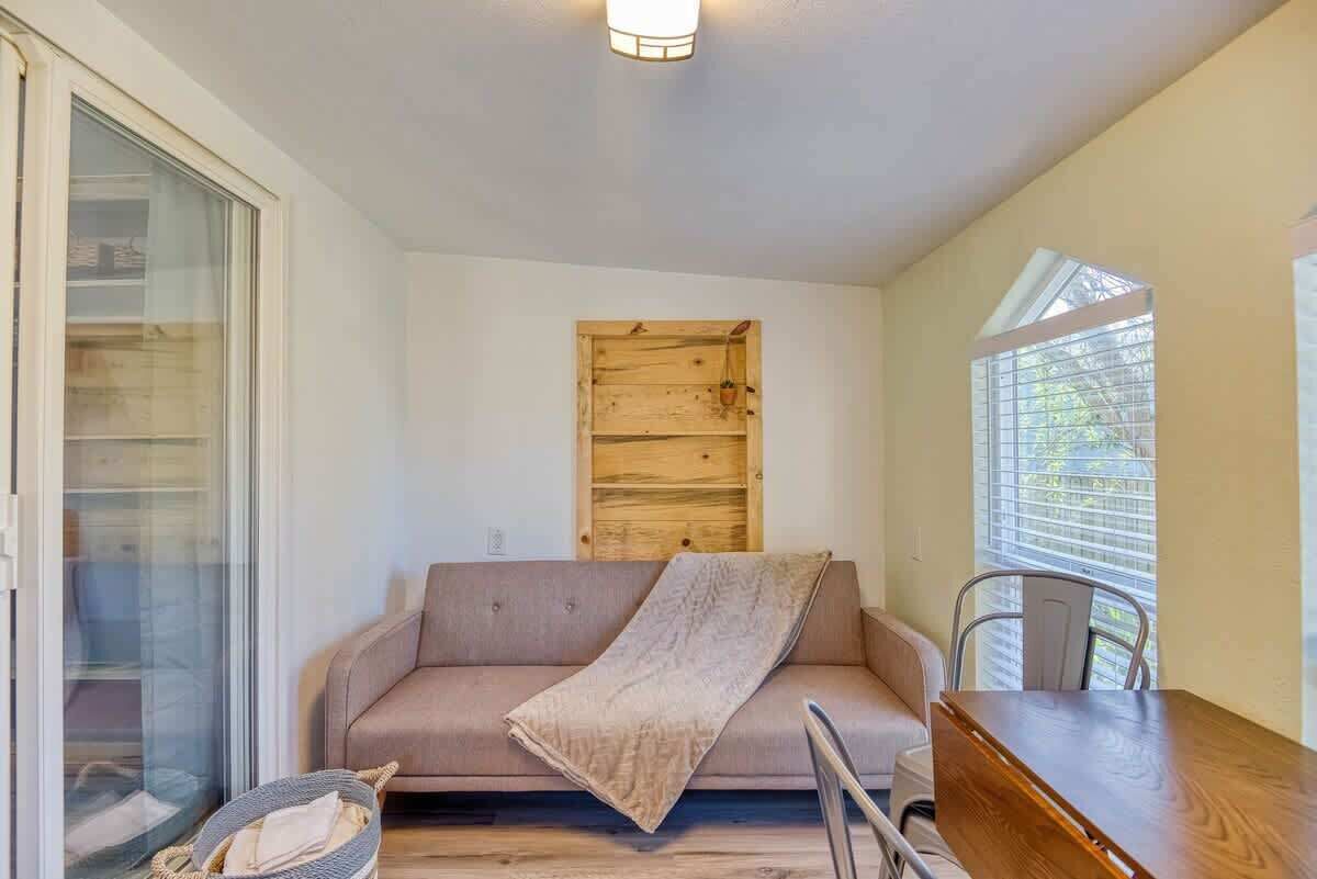 Een gezellige kamer met een bank, een klein tafeltje en een raam met jaloezieën.