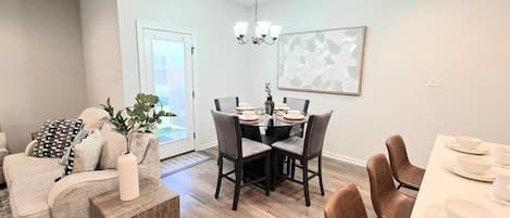A modern dining area with a round table, chairs, and a chandelier.