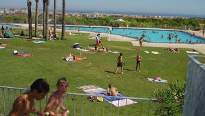 A pool area with multiple swimming pools, palm trees, and people sunbathing. - Chalet with air conditioning on beautiful park (Barcelona)