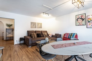 Ein modernes Wohnzimmer mit einer Couch, einem Esstisch und Kunstwerken an den Wänden.