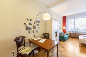 A living room with a wooden dining table, two chairs, a sofa, and a lamp.