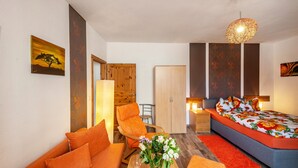 Een moderne slaapkamer met een bed, een oranje bank, een houten garderobe en een groot raam.