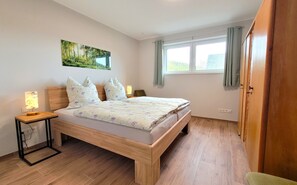 Una camera da letto con un letto, lampade da comodino, un quadro, una finestra con tende e un armadio in legno.