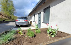 Un coche estacionado frente a un edificio con jardín.