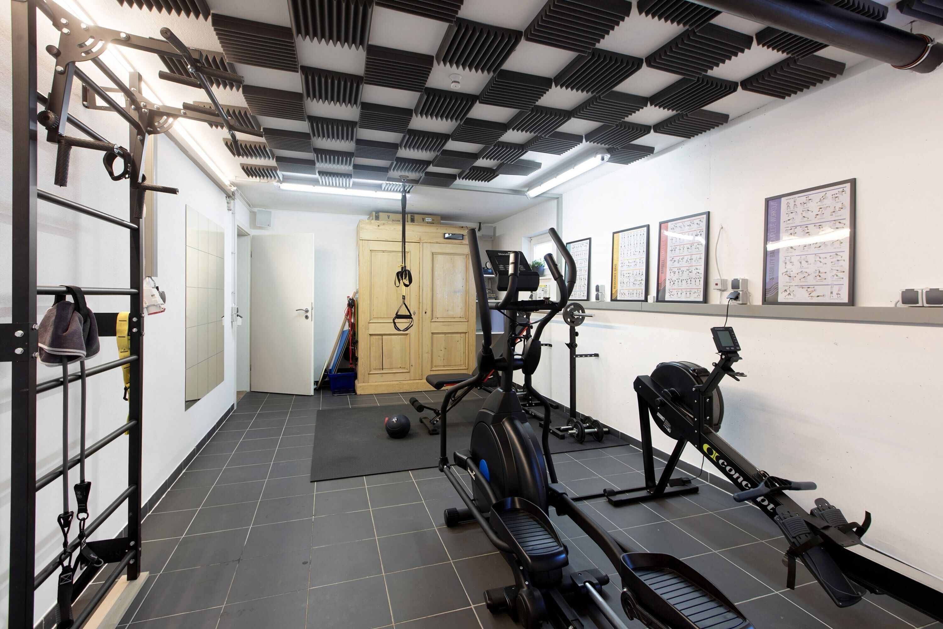 Un gimnasio con equipo de ejercicio, un estante de zapatos y una puerta que da a otra habitación.