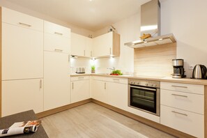 Ett modernt kök med vita skåp, en inbyggd ugn och en kaffebryggare.