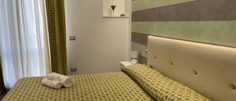 A hotel room with a bed, a nightstand, a lamp, and a wall with horizontal stripes.