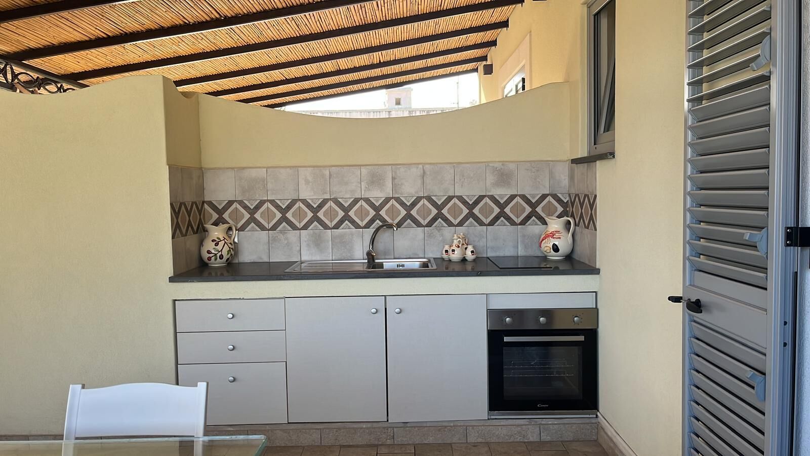 A compact kitchen with a tiled backsplash, a built-in oven, and a sink.