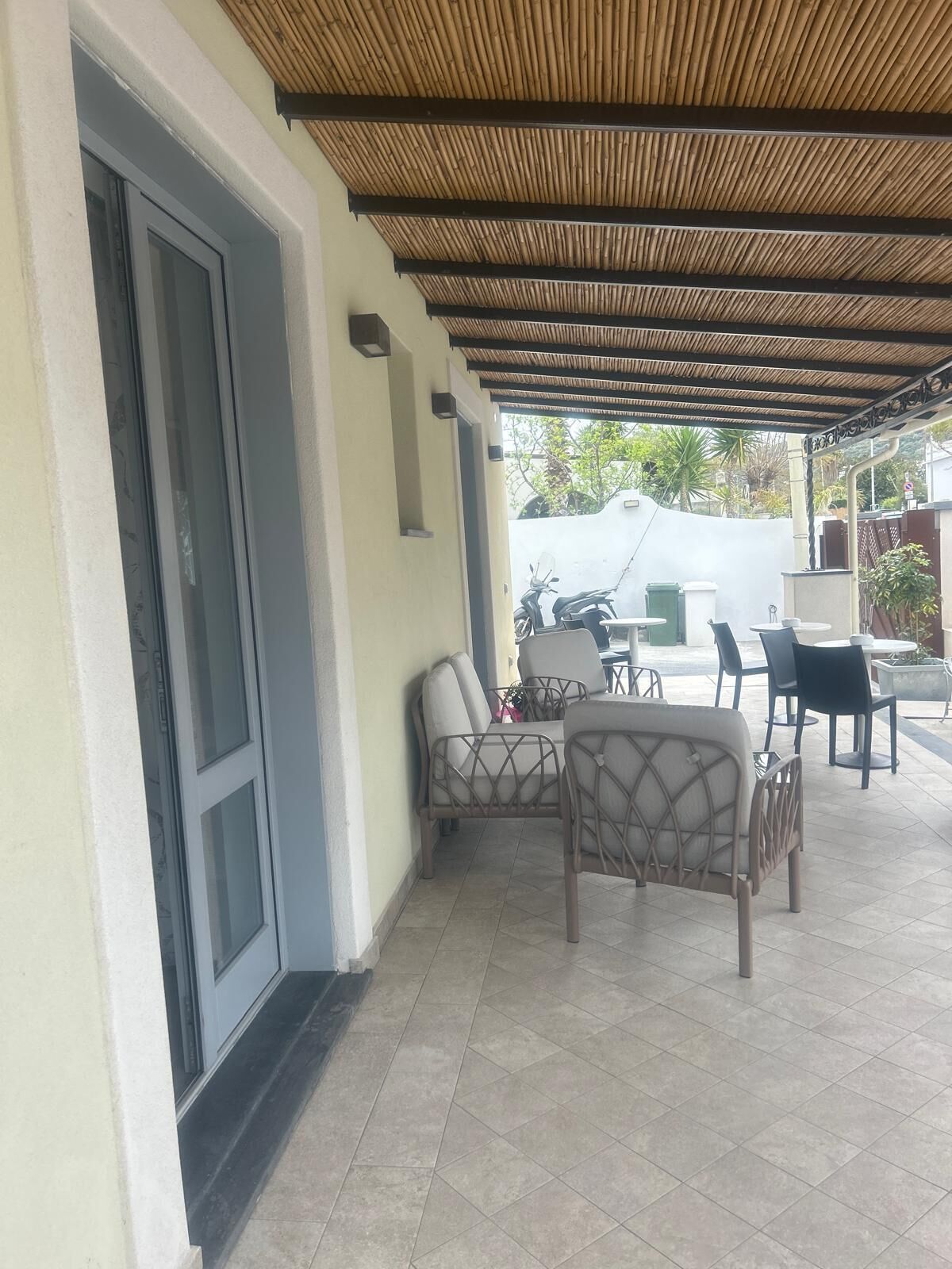 Eine Außenpatio-Terrasse mit überdachter Sitzecke, einer Tür und Blick auf die Straße.