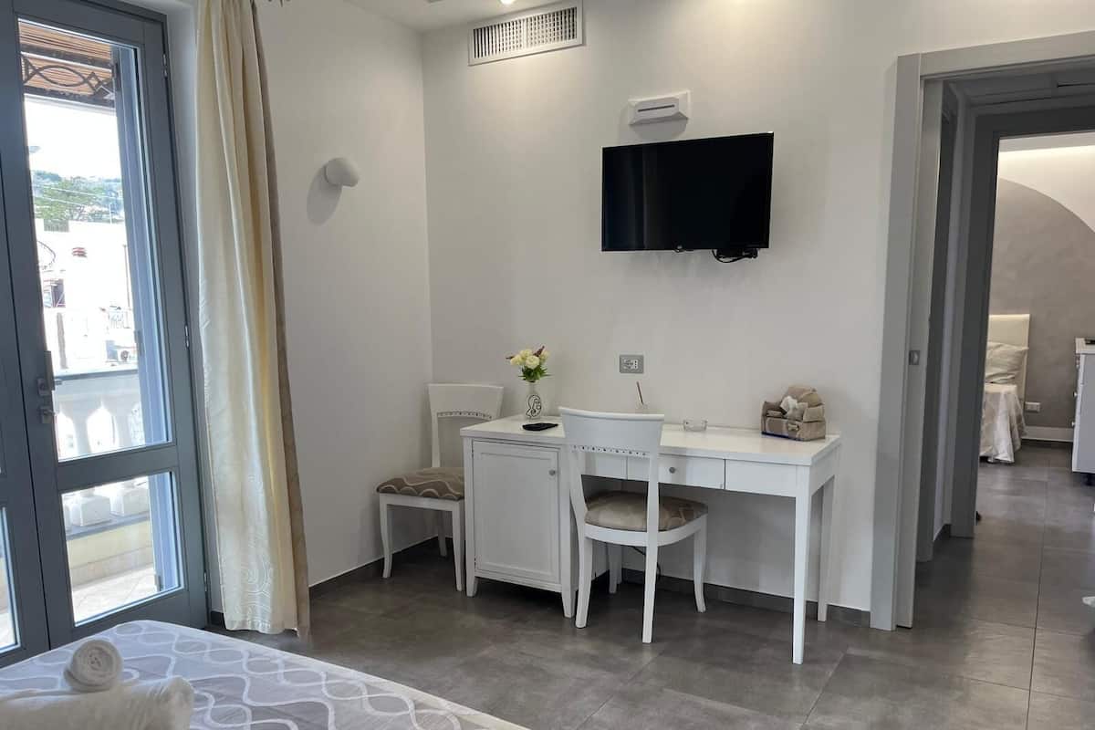 Un dormitorio moderno con una cama, un escritorio y un televisor.