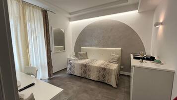 Una habitación de hotel moderna con una cama grande, un escritorio y un armario pequeño.