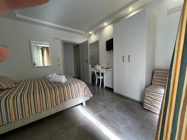 Una habitación de hotel con cama, escritorio, silla y armario.