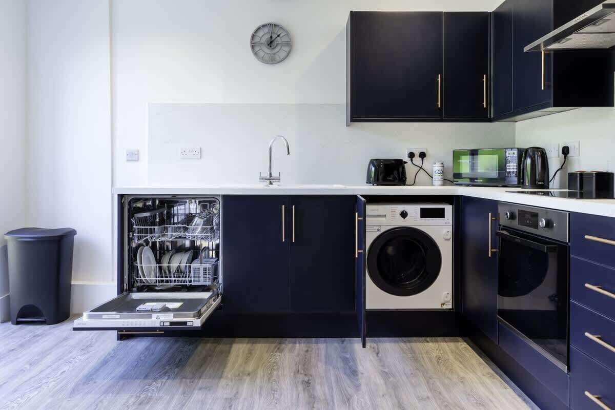 A compact kitchen with a dishwasher, washing machine, and oven.