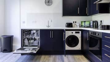 A compact kitchen with a dishwasher, washing machine, and oven.