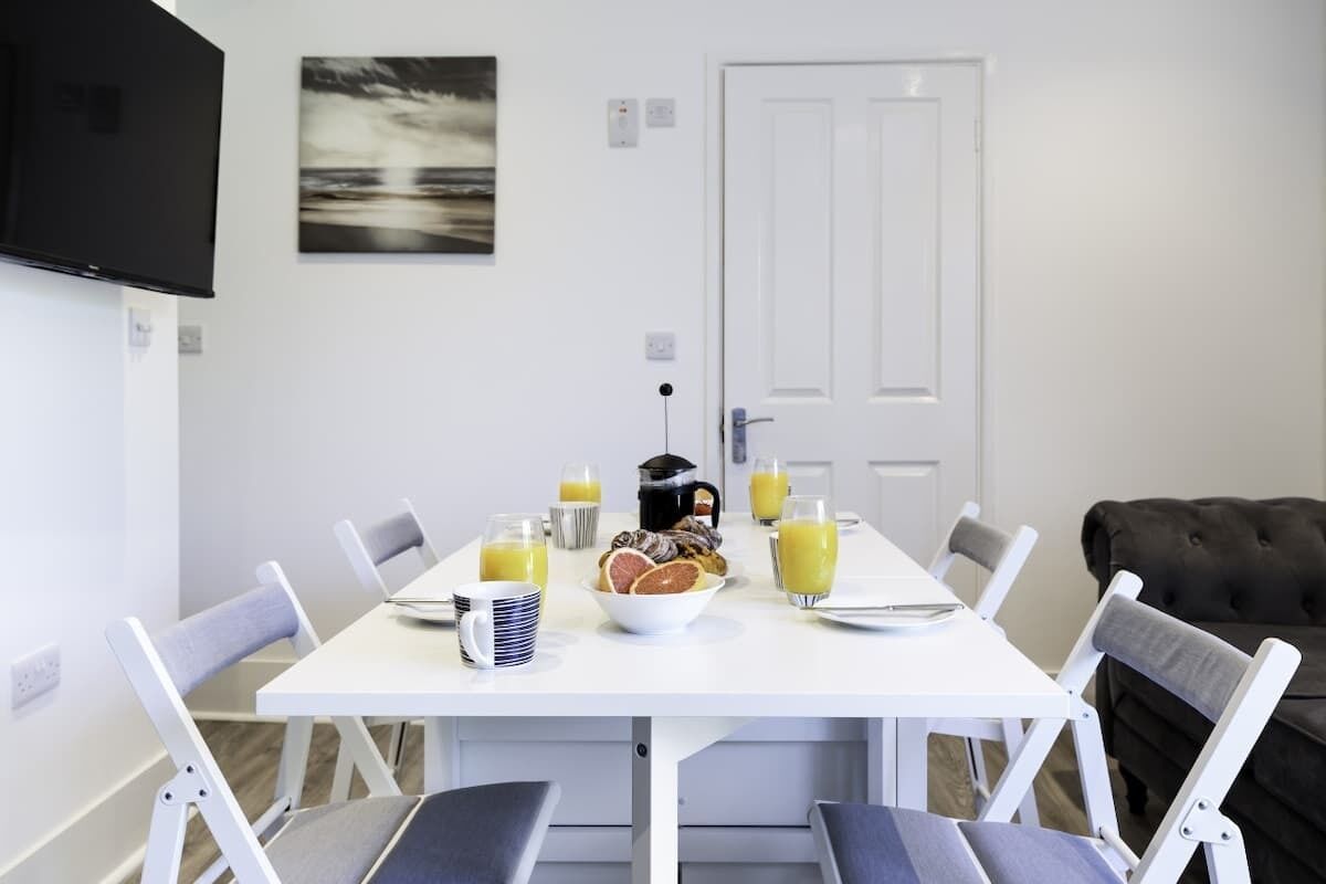 A dining area with a white table, chairs, and breakfast items.