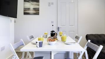 A dining area with a white table, chairs, and breakfast items.