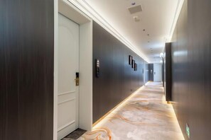 A hallway with a carpeted floor, a door on the left, and a wall-mounted television on the right. - Electric Machine Hotel (Yongji)