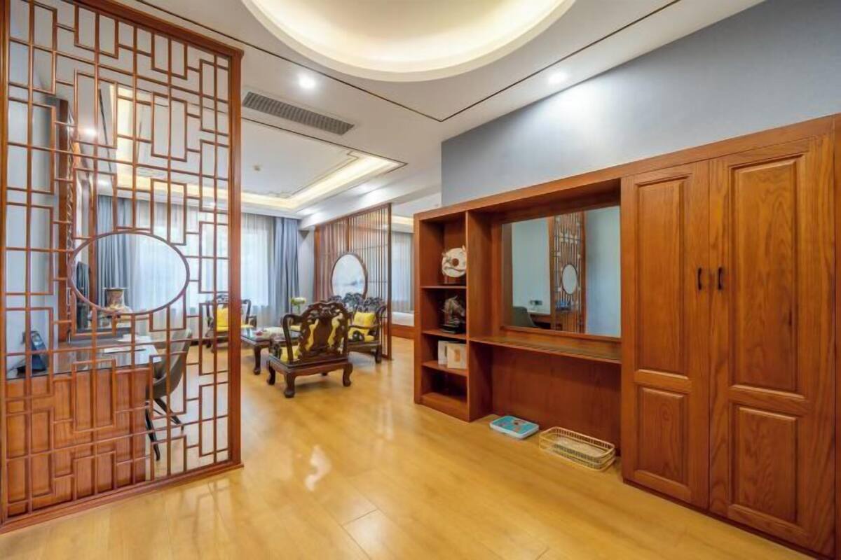 A traditional-style living room with wooden furniture, a decorative screen, and built-in shelves.