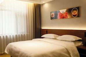 A hotel room with a large bed, a headboard, a wall-mounted artwork, and a window with curtains. - Electric Machine Hotel (Yongji)