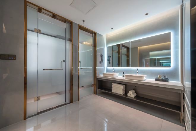 A modern bathroom with a glass-enclosed shower, a vanity with a mirror, and a towel rack.