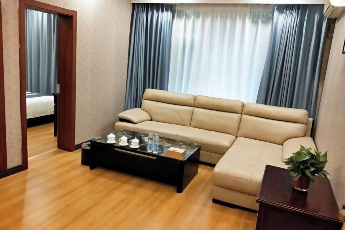 A living room with a beige sofa, a glass coffee table, and a wooden floor.
