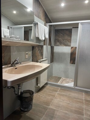 A modern bathroom with a sink, mirror, and shower. - Hotel HAAS (Bad Gastein)