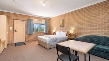 A hotel room with a bed, a sofa, a table, and a chair.