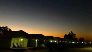 A row of tents with a sunset in the background. - Sam Resort and Camp (Jaisalmer)