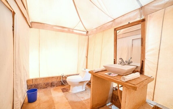 Un baño con toldo que incluye un inodoro, lavamanos y espejo.