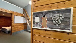 A wooden interior with a bunk bed, a framed list board, and a heart-shaped decoration. - Whispering Pines Haven (Redmond)