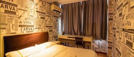 Una habitación de hotel con una cama, un escritorio y una pared cubierta de recortes de periódico.