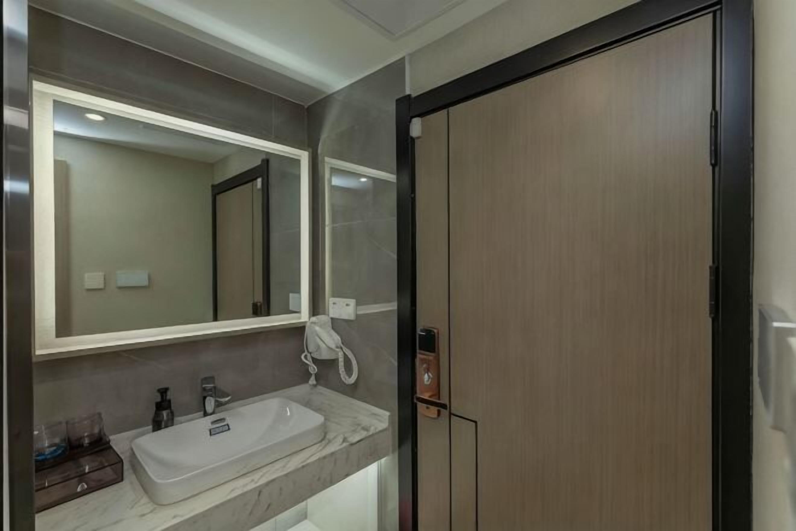 A bathroom with a marble sink, a large mirror, a wooden door, and a white telephone.