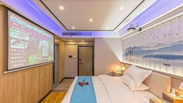 A hotel room with a bed, a wall-mounted TV, a painting, and a door.