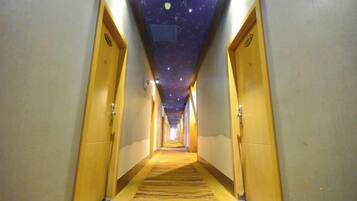 Un pasillo de hotel con techo estrellado, piso alfombrado y puertas de madera.