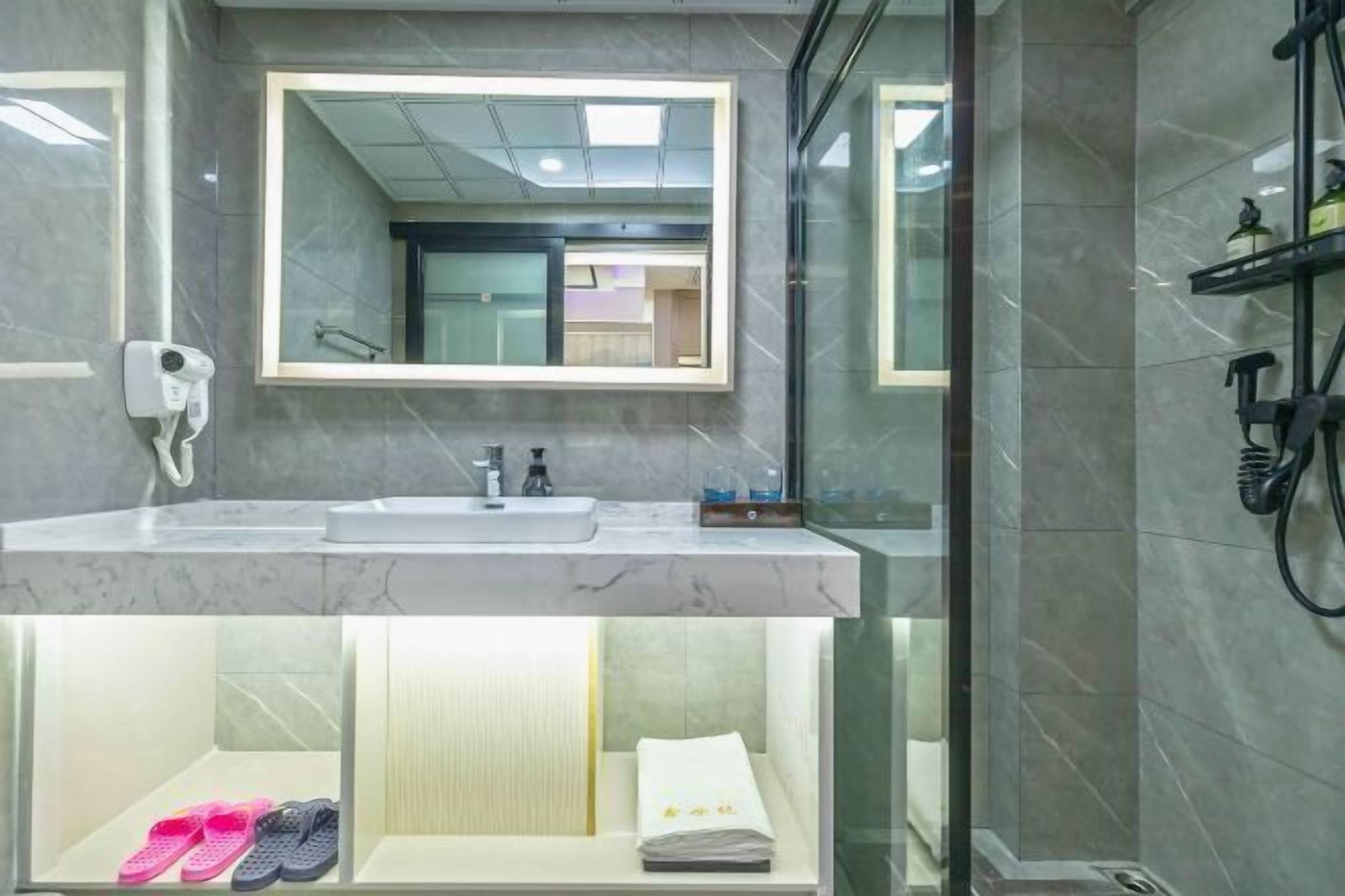 A modern bathroom with a large mirror, a sink, and a shower area.
