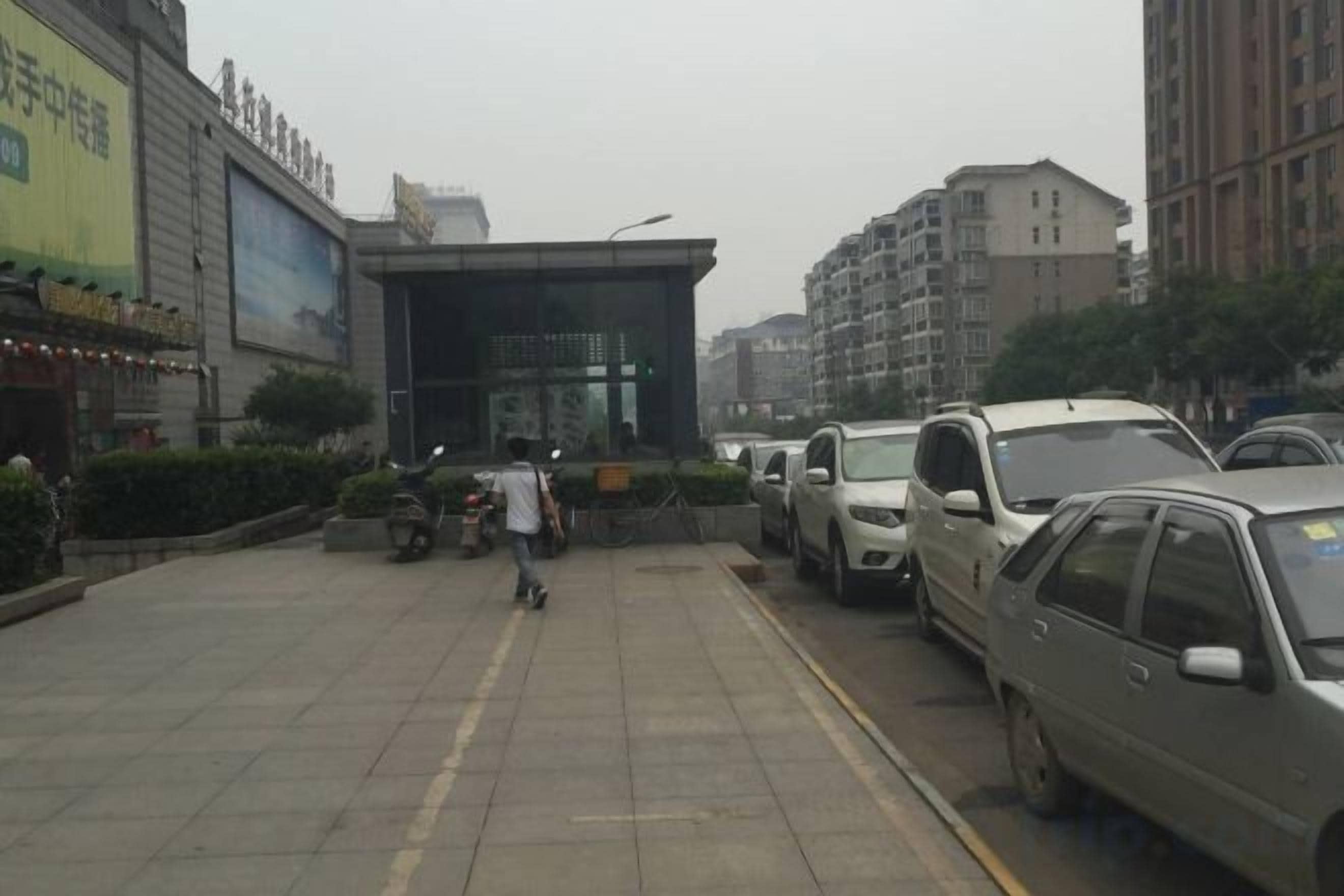 A parking lot with cars and a person walking.
