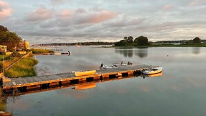 Un lac paisible, avec un quai et des bateaux, entouré de verdure et surplombé d’un ciel nuageux.