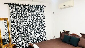 A bedroom with a bed, a wooden chair, a desk, and a mirror. - Swarna Derana Cozy Retreatment Jaela (Ja-ela)