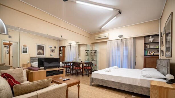 A well-lit room with a bed, a TV, a desk, and a dining area. - Syntagma square 1 bedrm 4 persons apartment by MPS (Athina)