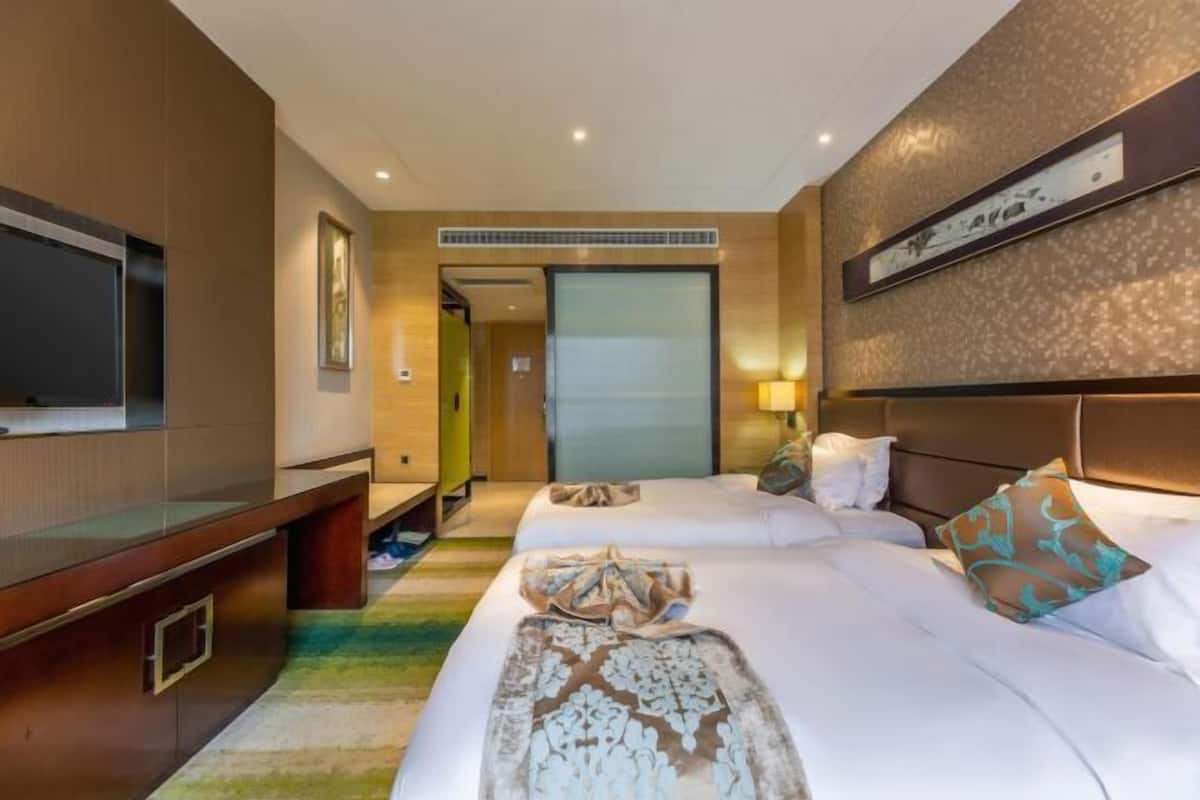 A hotel room with a bed, a TV, a desk, and a door leading to a bathroom.