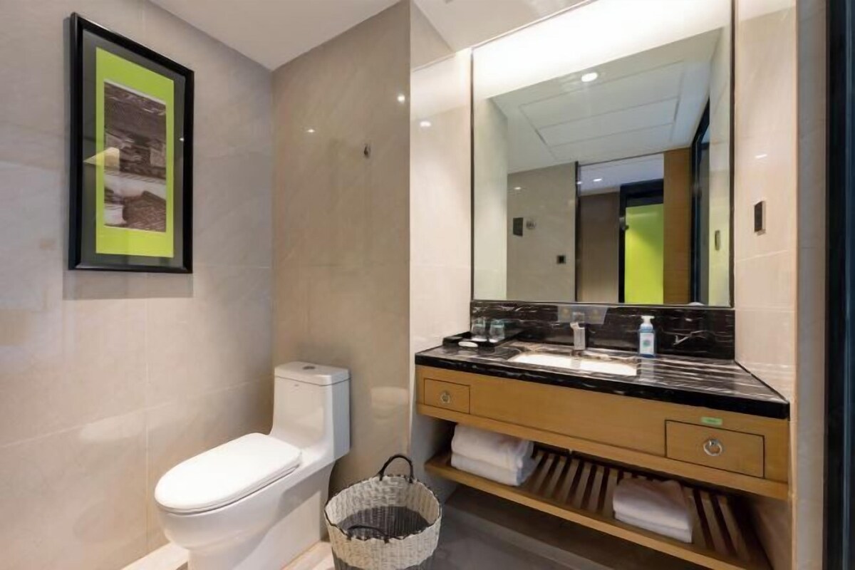 A modern bathroom with a toilet, a sink with a large mirror, and a basket.