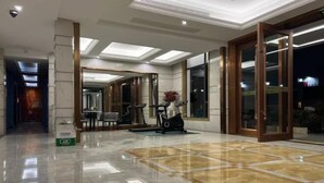 A spacious lobby with a polished marble floor, a seating area with chairs and a table, and a large mirror reflecting the space. - Xi Xi Holiday Hotel (Zhoushan)