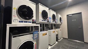 Een rij Aqua wasdrogers, aangedreven door munten, in een commerciële omgeving.