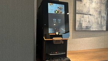 A coffee machine with a digital interface, a coffee cup, and a coffee pot.
