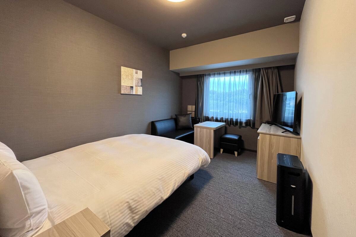 Une chambre d’hôtel équipée d’un lit, d’un bureau, d’une chaise, d’une télévision et d’une petite table.