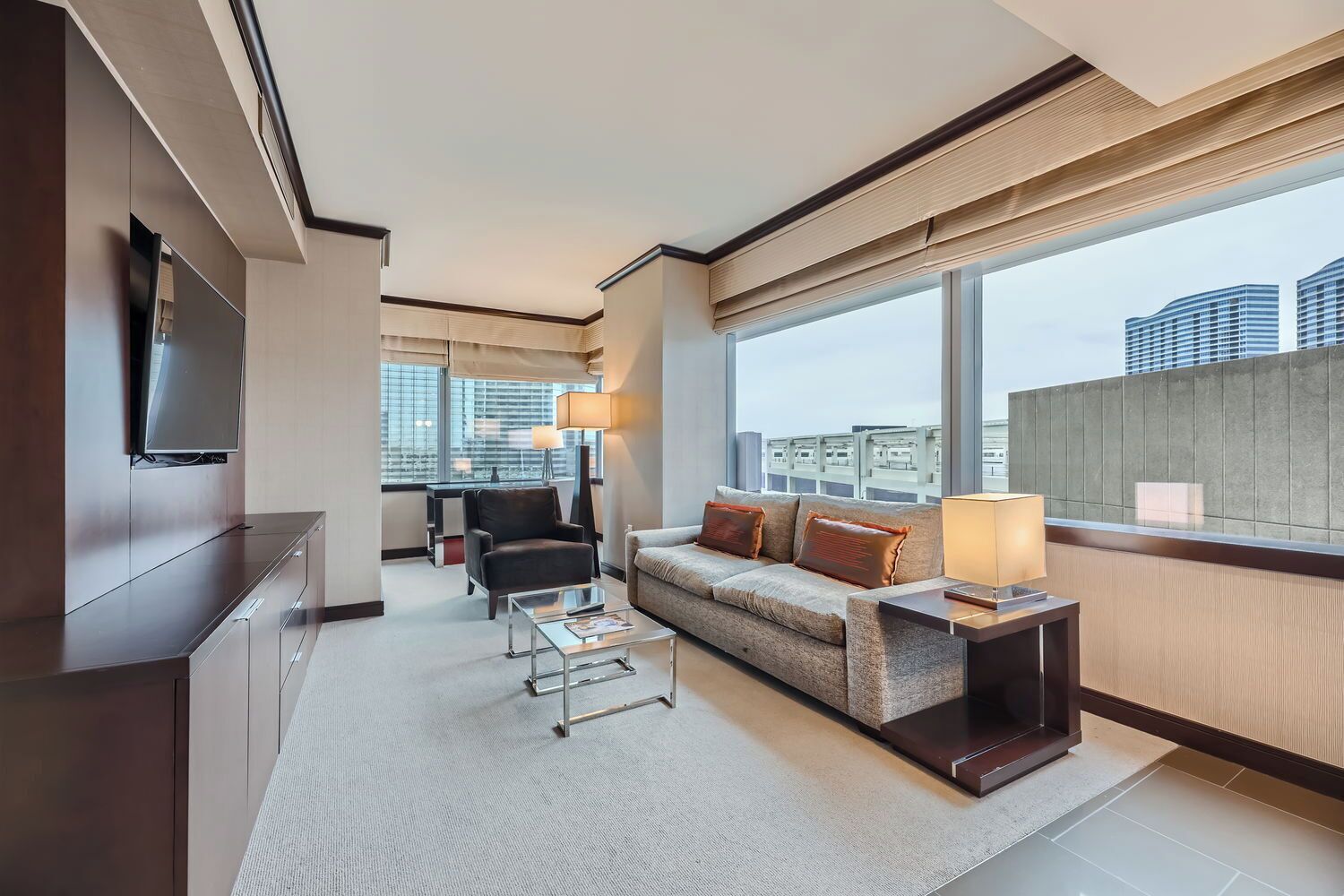 Une chambre d’hôtel moderne, équipée d’un canapé, d’un fauteuil et d’un téléviseur fixé au mur.