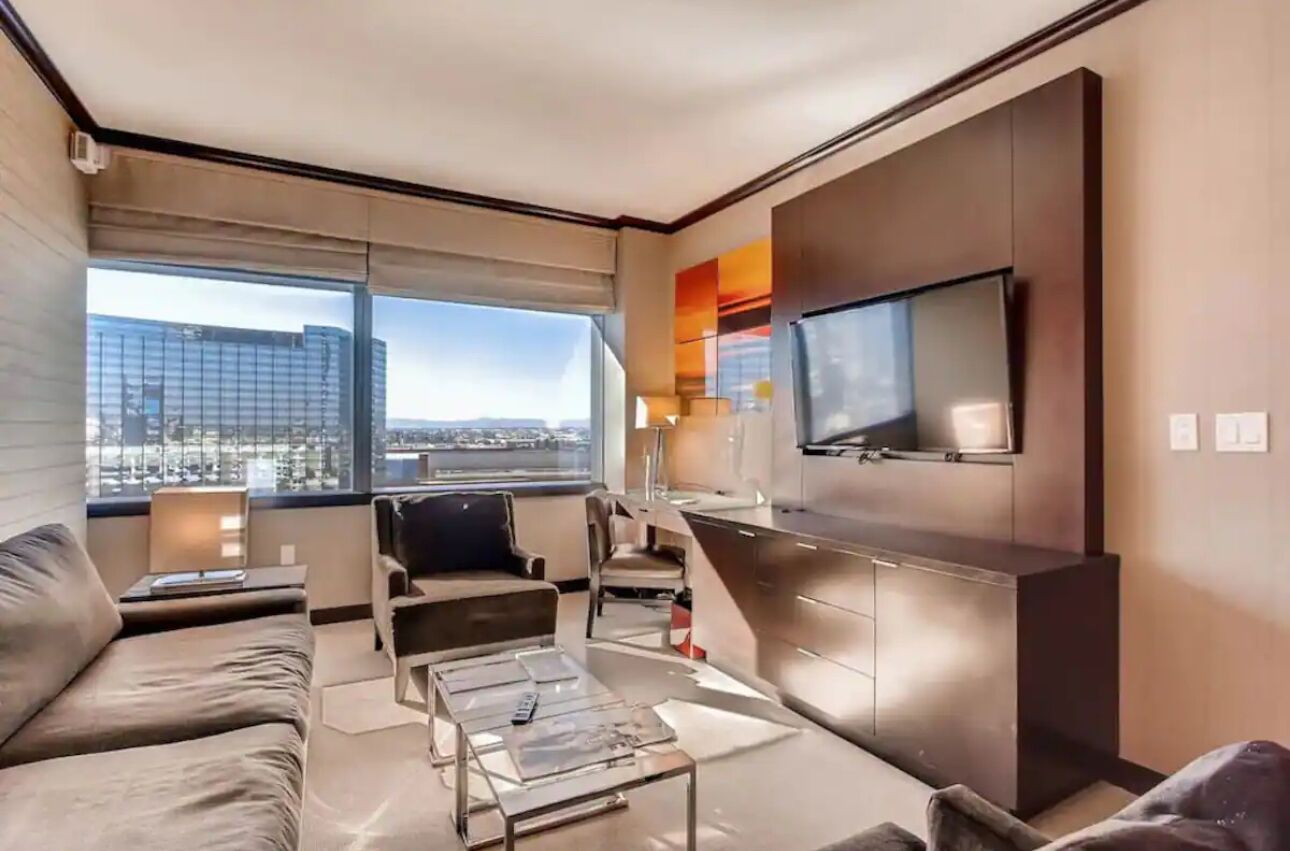 A modern living room with a sofa, coffee table, and a TV mounted on the wall.