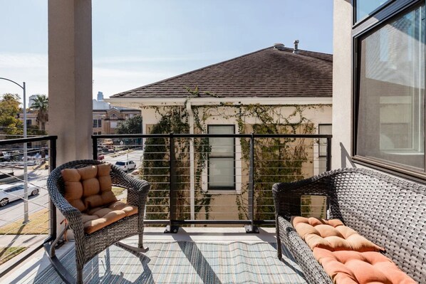 A balcony with wicker furniture, a view of a building with ivy, and a clear sky. - Capital View Condos Downtown Austin  (Austin)