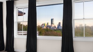 A room with a large window, black curtains, and a view of a city skyline. - Townhomes In Downtown Austin  (Austin)