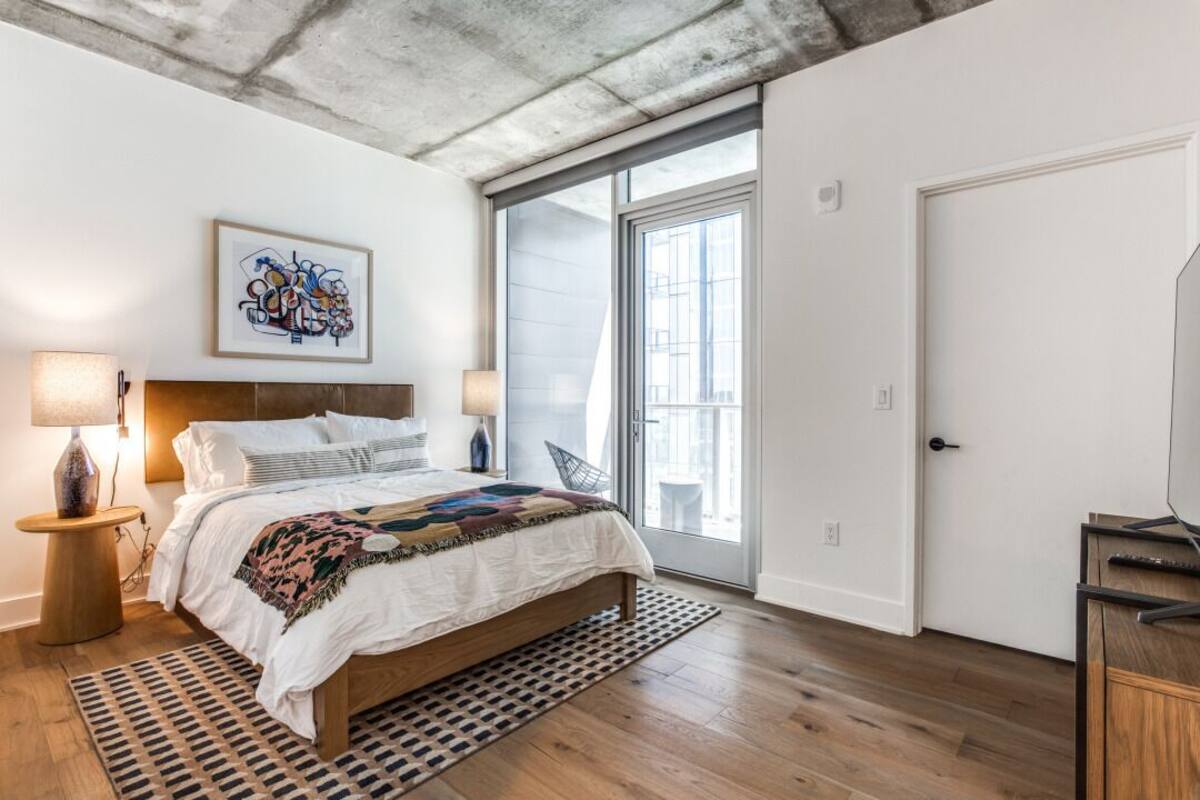 Un dormitorio con cama, ventana, puerta y una obra de arte en la pared.